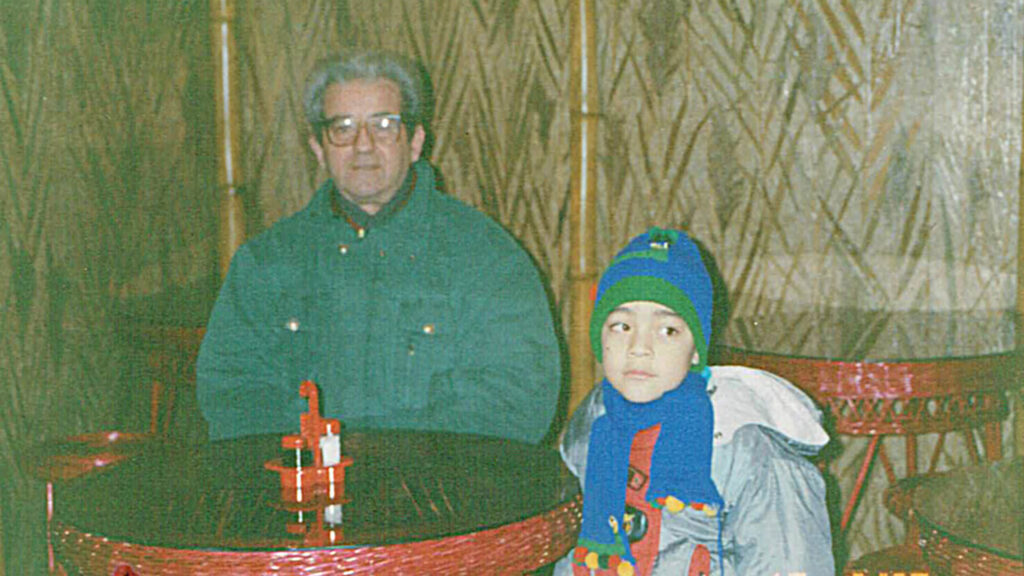 An older man and a child sitting together at a cafe table.
